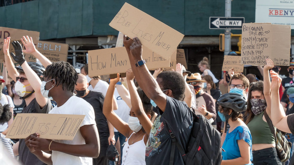 Crowds, holding homemade signs reading "Black Lives Matter" and "Enough is Enough," march in New York City.